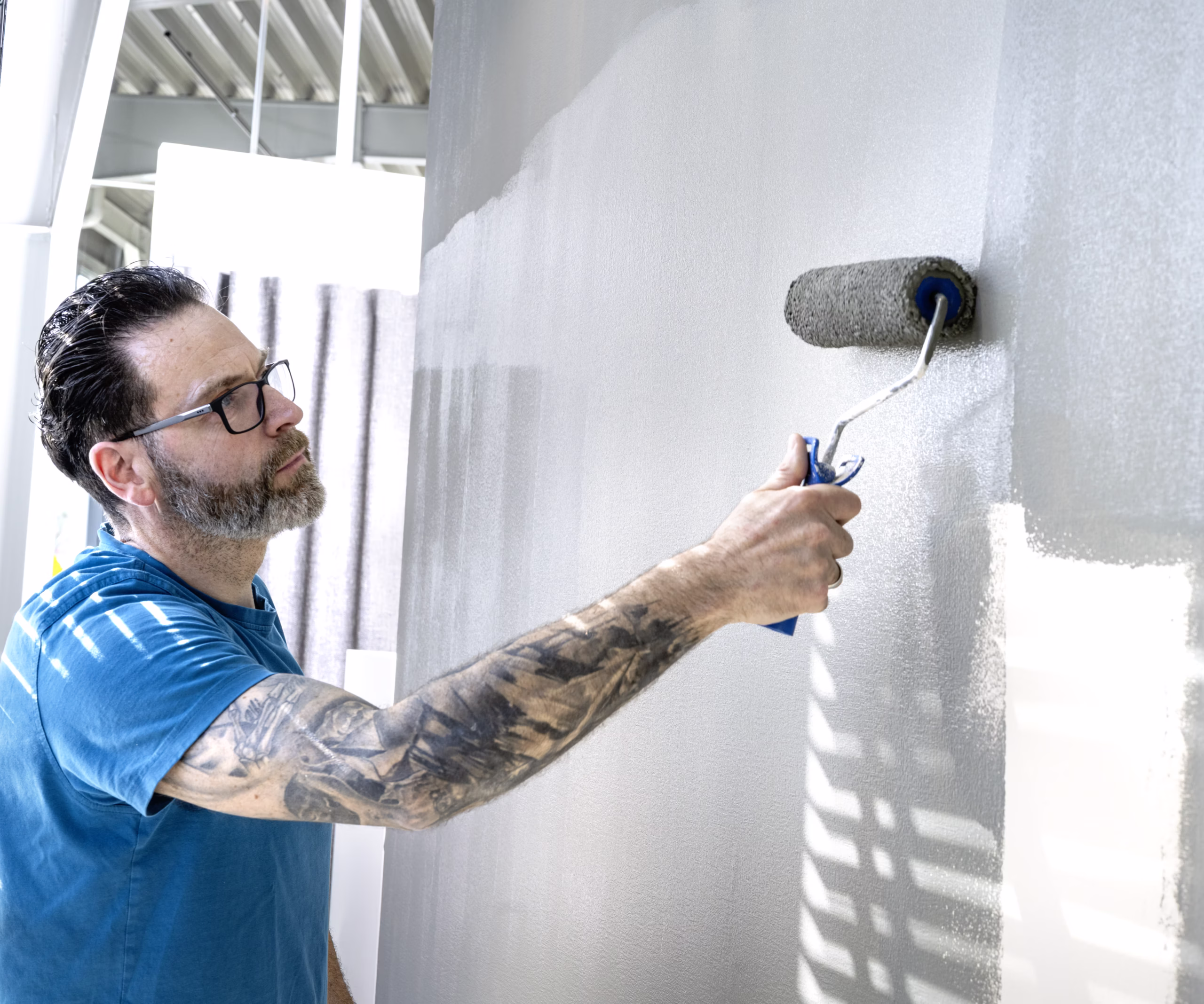 Maler streicht eine Wand mit der Farbrolle