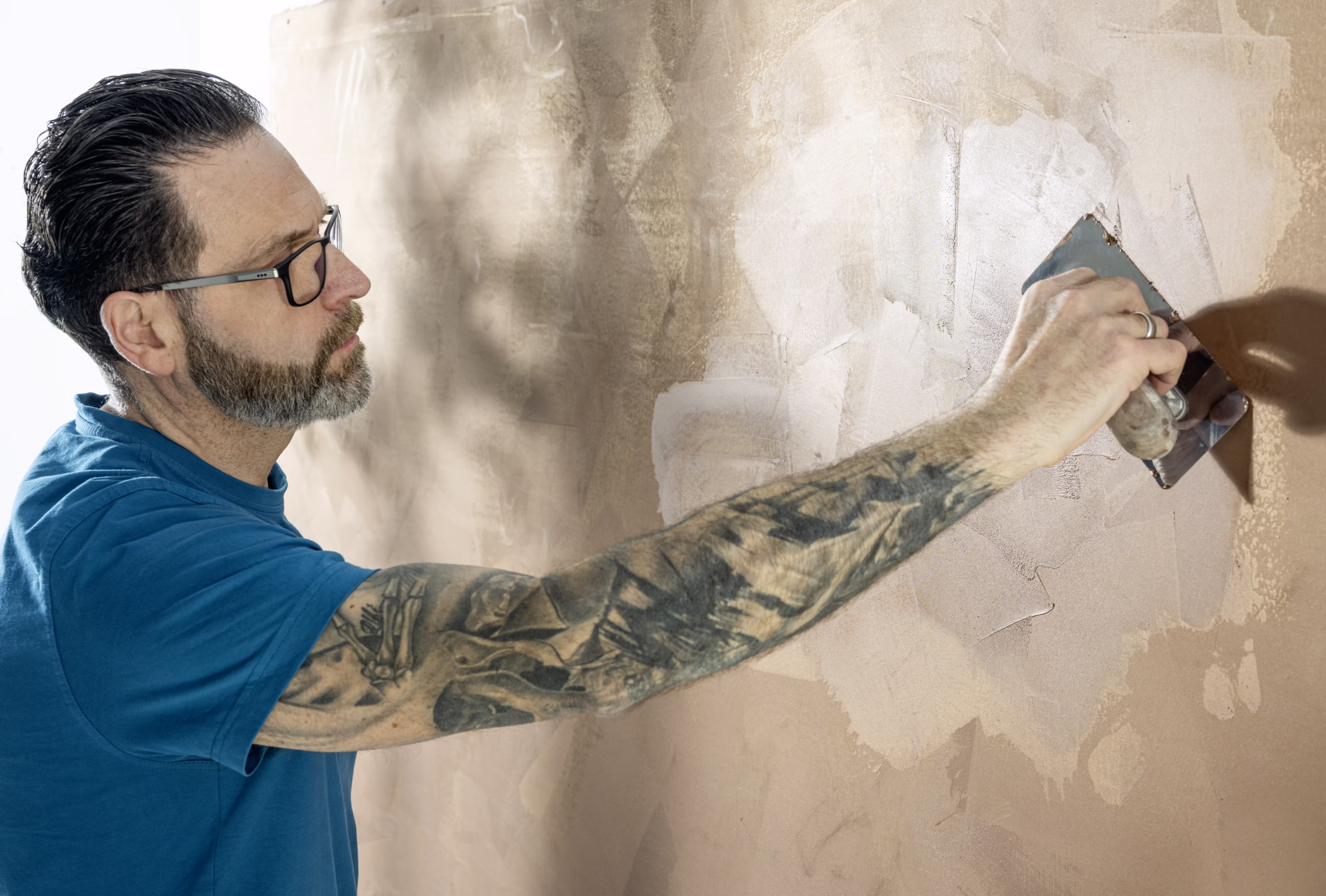 Maler gestaltet eine Wand in Spachteltechnik mit warmem Farbton